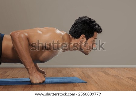 Man doing pushups in front of a plain background