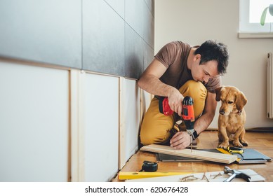 Man Doing Renovation Work At Home Together With His Small Yellow Dog