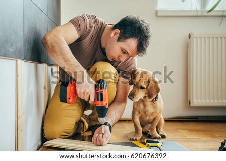 Man doing renovation work at home together with his small yellow dog