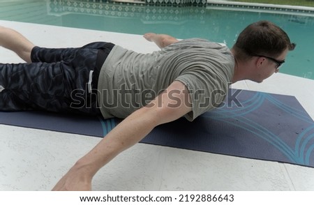Man doing reverse snow angels exercise. He is doing an at-home workout consisting of calisthenics on a yoga mat.