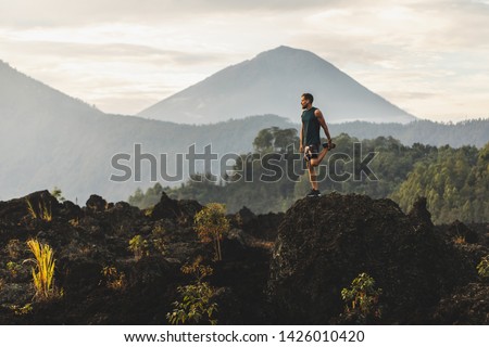 Man doing stretching and preparing for workout and running outdoors. Amazing mountain view on background. Adventure sports concept.
