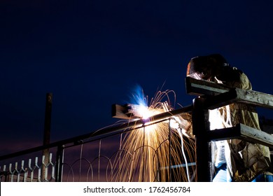 man doing welding work, by an arc manual apparatus, in the dark