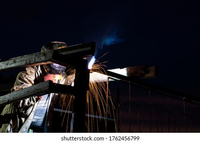 man doing welding work, by an arc manual apparatus, in the dark