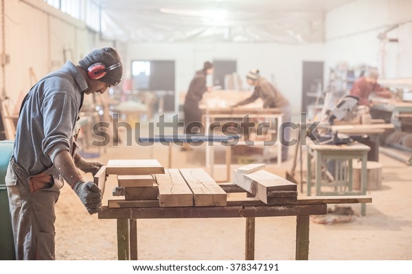 Man doing woodwork in carpentry. Carpenter work\
on wood plank in workshop