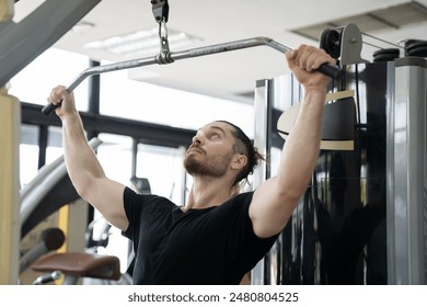Man doing workout exercise with thrust of the upper block in gym. Man training hard in sport gym. Man pulling weights in seated cable row machine. Sport fitness concept
