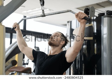 Man doing workout exercise with thrust of the upper block in gym. Man training hard in sport gym. Man pulling weights in seated cable row machine. Sport fitness concept