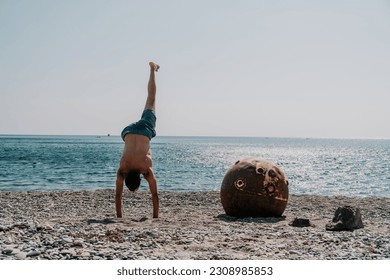 Man doing yoga exercise outdoors standing on old rusty floating marine mine on the beach with rocky shore and sea background. Healthy lifestyle, pollution, nature protection, war and peace concept. - Powered by Shutterstock