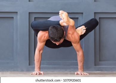 Man Doing Yoga Exercises And Practicing Handstand Balance Pose On Grey Urban Background.