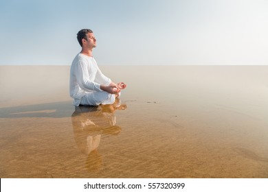 Man doing yoga meditation in Lotus position sitting in the sea water - Powered by Shutterstock