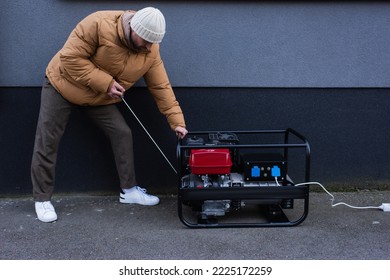 man in down jacket starting power generator during electricity shutdown