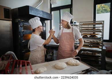 Man with down syndrom helping prepair bread in bakery with his colleague. Concept of integration people with disability into society. - Powered by Shutterstock