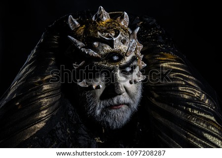 Man with dragon skin and gray beard, alien or reptilian makeup. Monster with sharp thorns and warts. Demon head isolated on black, horror and fantasy concept.