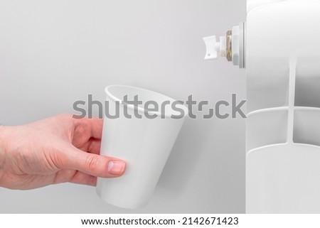 A man is draining water and air for adjusts autonomous heating system at home into a paper cup. Selective focus