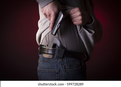 A Man Drawing A Conceal Carry Pistol From An Inside The Waistband Holster IWB.