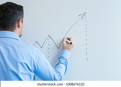 A Man Drawing A Graph On A White Board