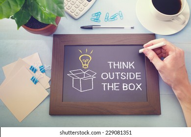 Man drawing Think Outside the Box and idea light bulb little blackboard