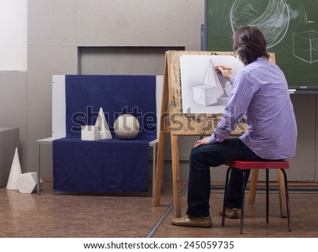 A man draws a pencil sitting at his easel.