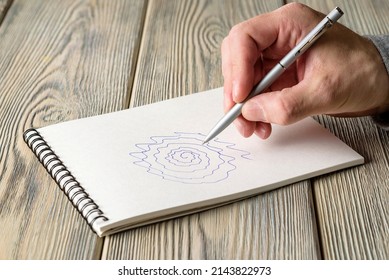 A Man Draws An Uneven Spiral In A Notebook. Test For Essential Tremor And Parkinson's Disease.