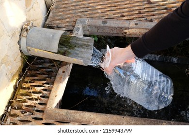 A man draws water from a spring into a plastic bottle
