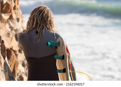 Man with dreadlocks carrying a surfboard down to the beach - Powered by Shutterstock