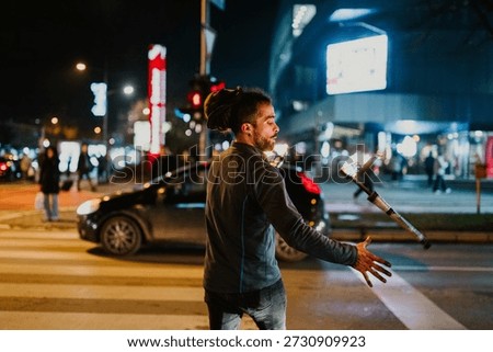 Man with dreadlocks performing fire juggling on a city street at night, entertaining passersby with his show