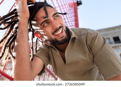 Man with dreadlocks smiling brightly, feeling happy in the warm summer sun