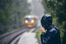 Mann In Roter Jacke Auf Bahnsteig Gegen Zug Bei Starkem Regen.