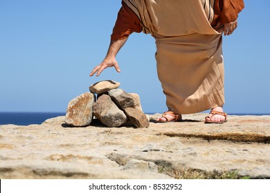 Man dressed in anicent clothing standing by a pile of stones bending over to pick one up - concept   sin, punishment,  Stoning was used in many ancient cultures for some crimes.
