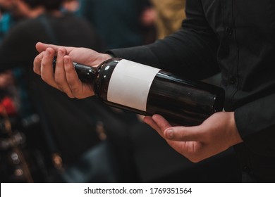 man dressed in black holds a bottle of wine in his hand. Holding bottle wine - Shutterstock ID 1769351564