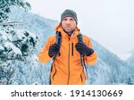 Man dressed bright orange softshell jacket with backpack have trekking on the winter mountains route. Active people or survival in the nature concept image.