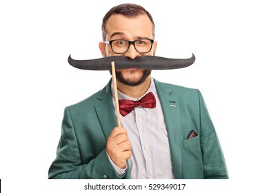 Man Dressed In A Green Coat Holding A Fake Moustache On His Face Isolated On White Background