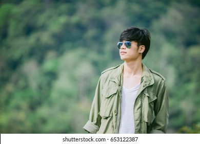 Man Dressed In Jeans Holding Guitar Case In Nature Outdoor.