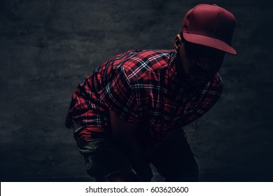 A man dressed in a red fleece shirt and a cap over posing in a shadow.