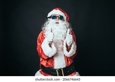 Man Dressed As Santa Claus With Victorian Style Welder Goggles, Raising Thumbs Up, On Black Background. Concept Of Christmas, Santa Claus, Gifts, Celebration.