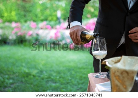 A man dressed in a sharp suit is carefully pouring champagne into a sparkling glass, creating an inviting atmosphere of celebration and joy