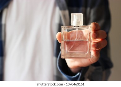 
a man dressed in urban style holds perfume. man's fragrance. minimalism, design, top. 