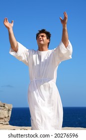 A Man Dressed In White Robe With Hands Raised In Spiritual Devotion, Praise Or Happiness.