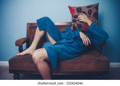 Man In Dressing Gown Hiding Behind Cushion