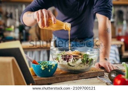 man dressing salad. he is preparing food in his kitchen