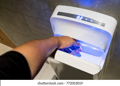 Man Dries Wet Hand In Modern Vertical Hand Dryer In Public Restroom WC