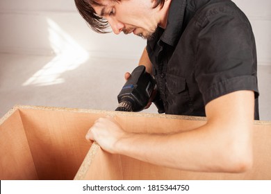 A Man Drills A Hole In A Closet Using A Drill. Cabinet.