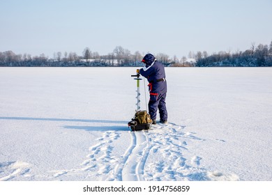 A Man Drills Holes In The Ice For Ice Fishing With An Electric Auger. Ice Fishing Using An Electric Auger.