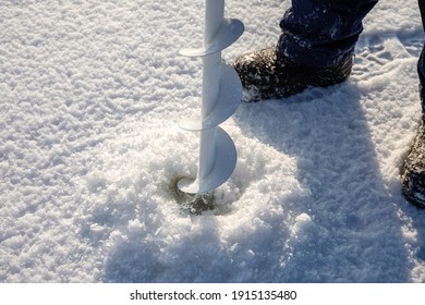 A Man Drills Holes In The Ice For Ice Fishing With An Electric Auger. Ice Fishing Using An Electric Auger.