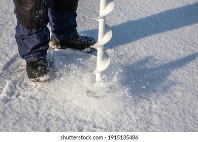 A Man Drills Holes In The Ice For Ice Fishing With An Electric Auger. Ice Fishing Using An Electric Auger.