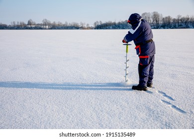 A Man Drills Holes In The Ice For Ice Fishing With An Electric Auger. Ice Fishing Using An Electric Auger.