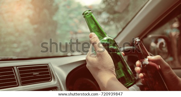 Man drink\
beer while driving car. Driving in a state of intoxication.don\'t\
drink and drive concept\
