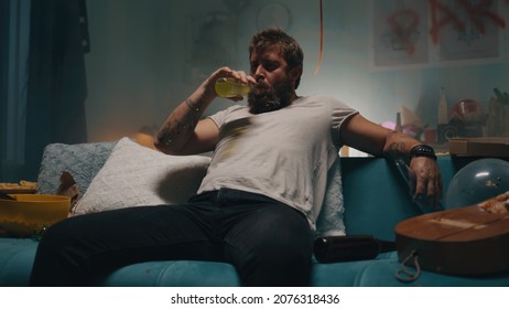 Man Drinking Alcohol On Sofa In Smoky Room