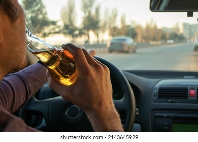 A man drinking alcohol while driving. Drunk driving concept.