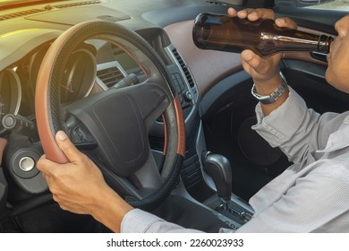 a man drinking alcohol. Drinking while driving can cause an accident.