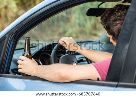 Man drinking alcohol while driving a car